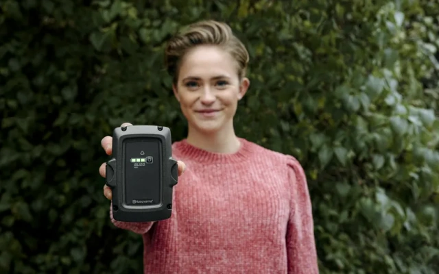 Djevojka pokazuje bateriju za Husqvarna uređaje