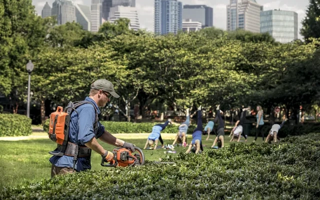 Muškarac obrezuje živu ogradu u parku s baterijskim škarama Husqvarna