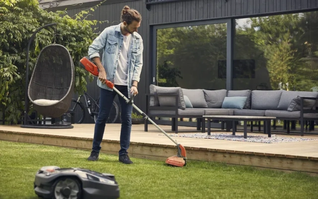 Muškarac uređuje travnjak s Husqvarna trimerom